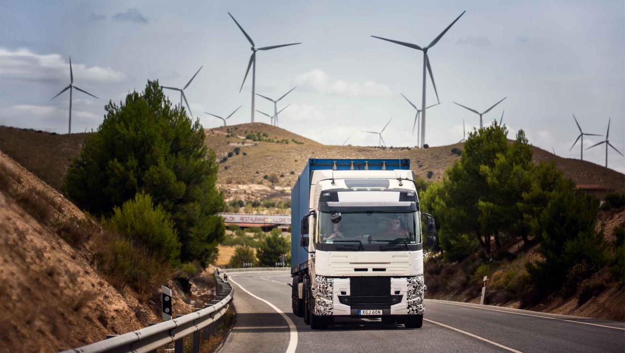 Випробувальна вантажівка на дорозі в Іспанії з вітрогенераторами на задньому плані